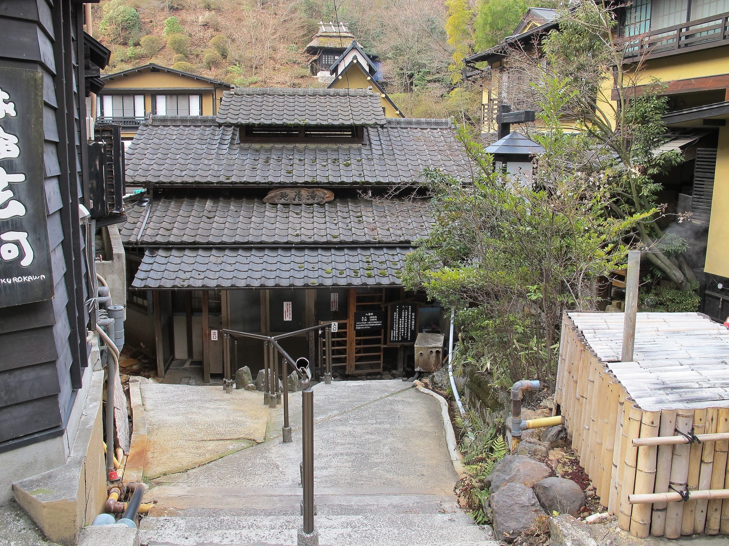 A stone path leads down to a tiled timber bathhouse among the inns of Kurokawa Onsen.