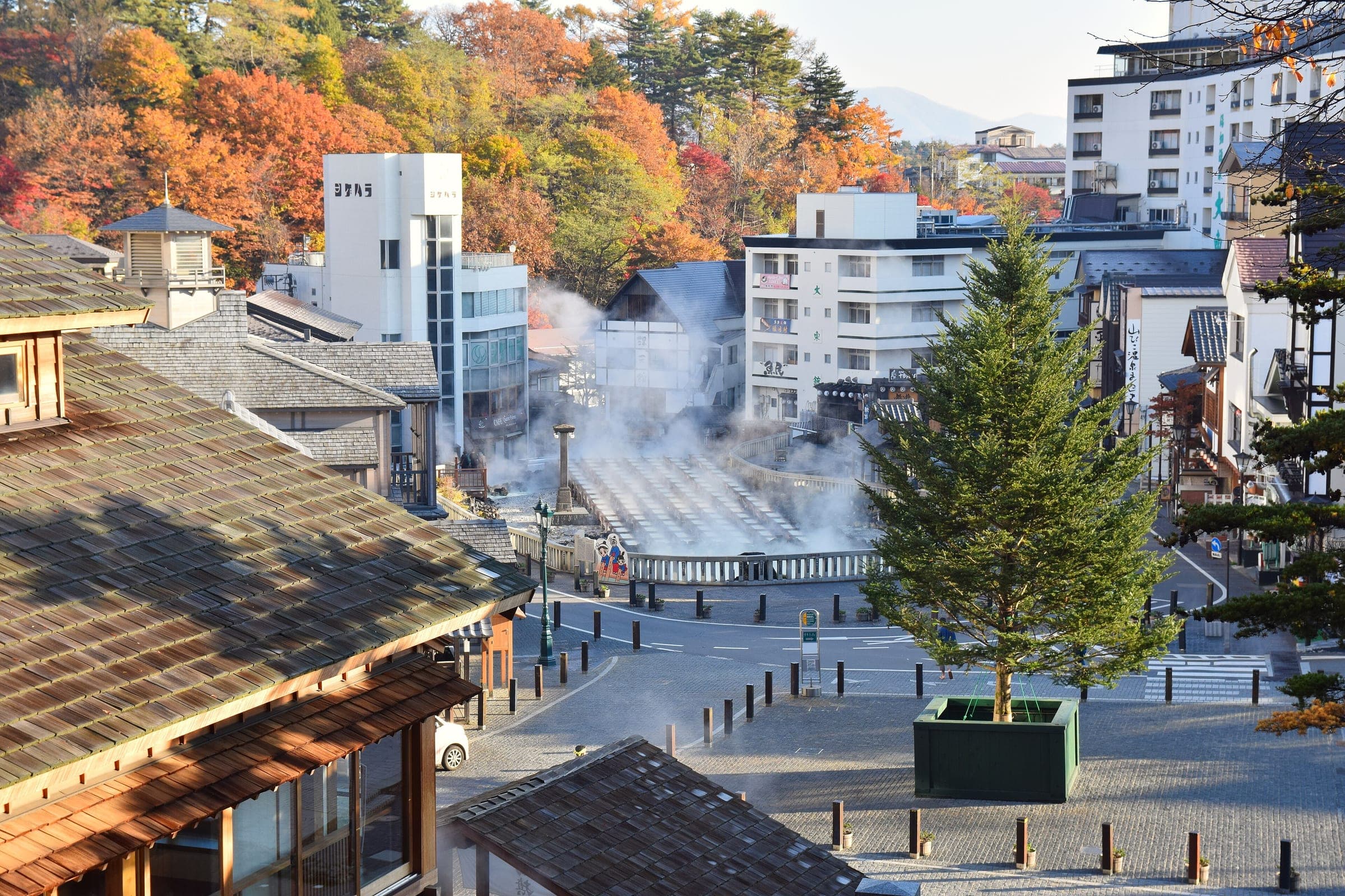 Steam rises past a stone lantern on the rocks at the edge of Kusatsu's Yubatake