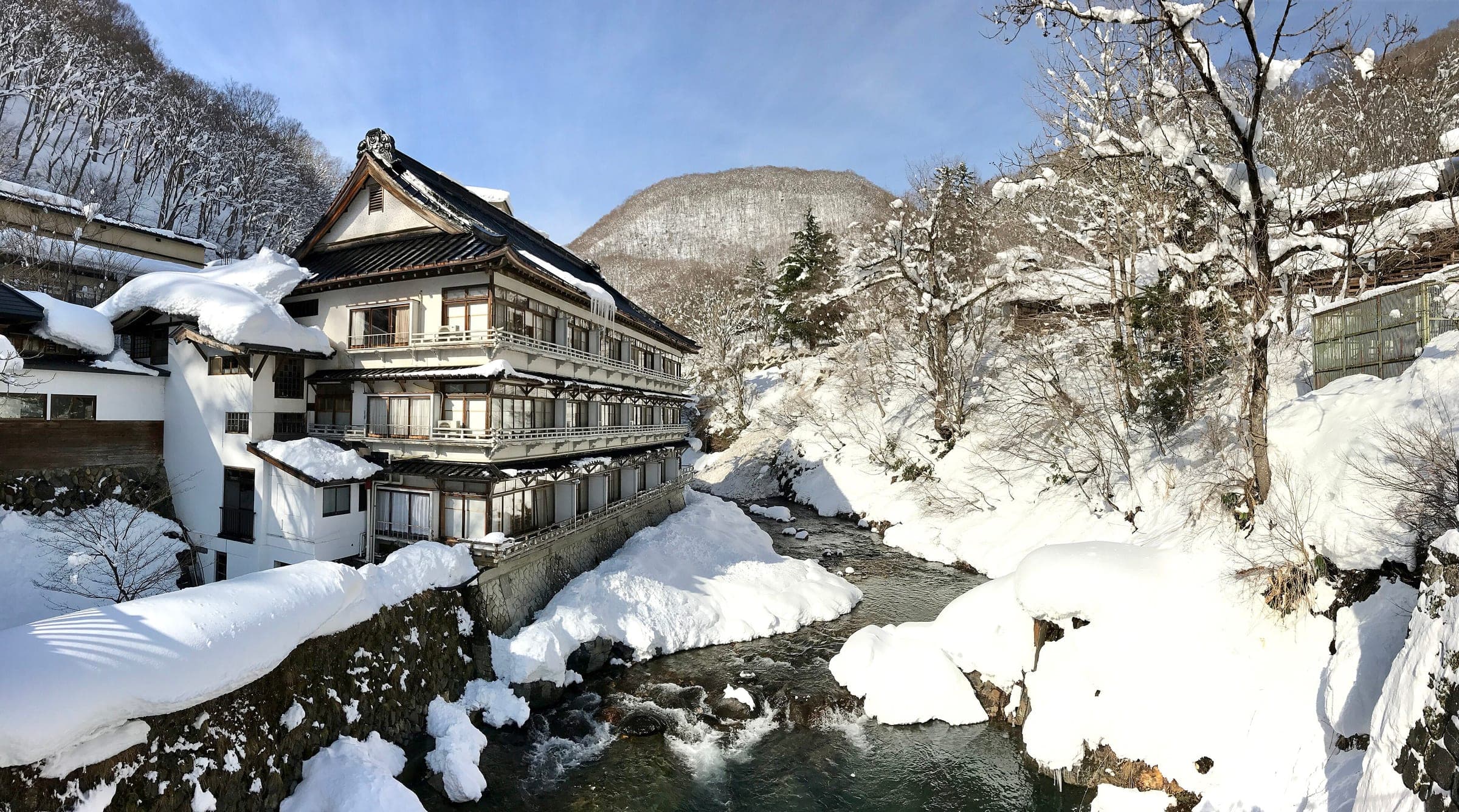 Deep snow banks the Takaragawa river below the wooden Osenkaku inn at Takaragawa Onsen in January