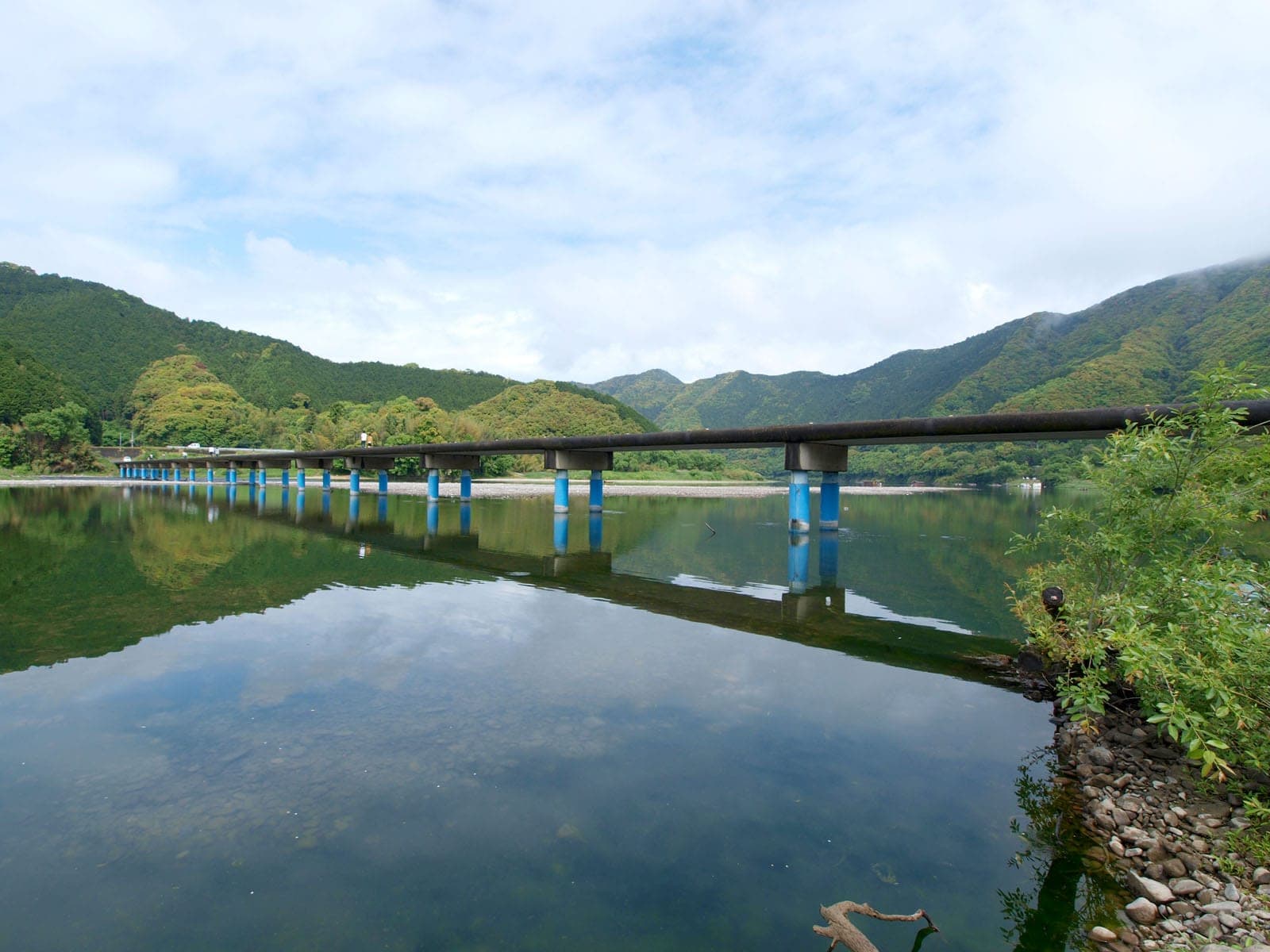 The low Sada sinking bridge crosses the still, green Shimanto River in Kochi in May