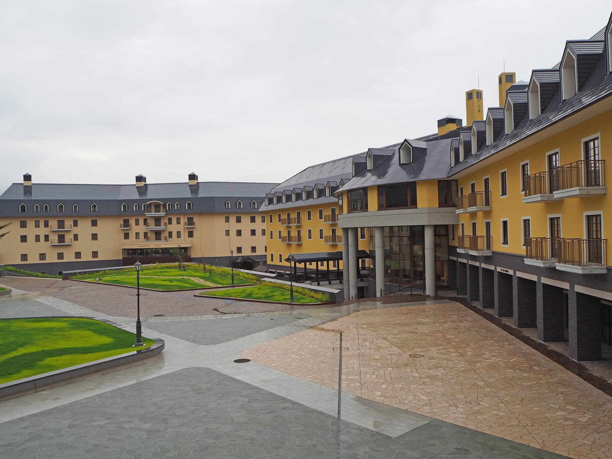 Yellow hotel wings with grey mansard roofs frame the courtyard at Arai Mountain Resort
