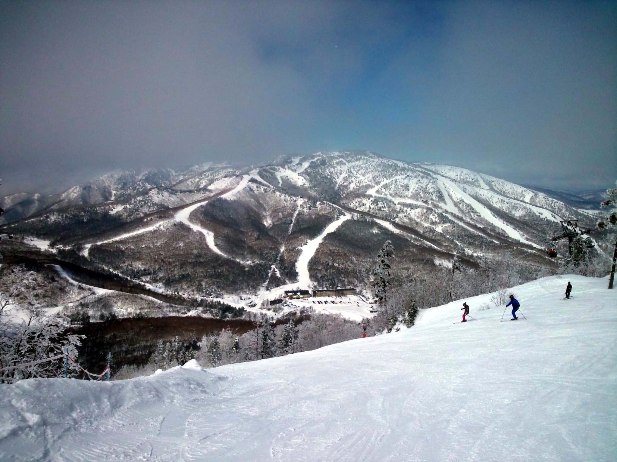 Riders stop on a Higashidateyama run facing the long trails of Mount Yakebitai across the valley